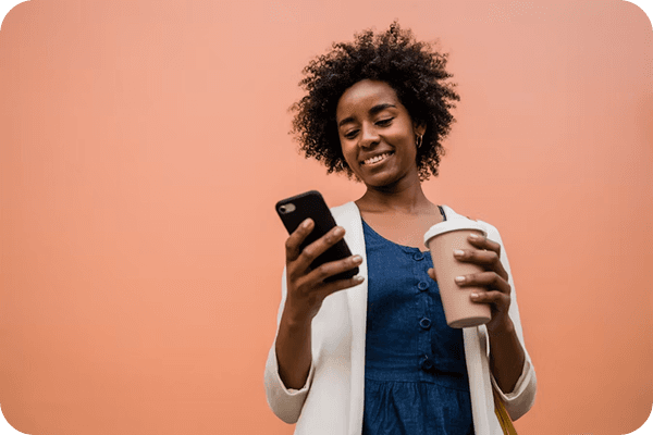 A young person smiling while looking at a phone.